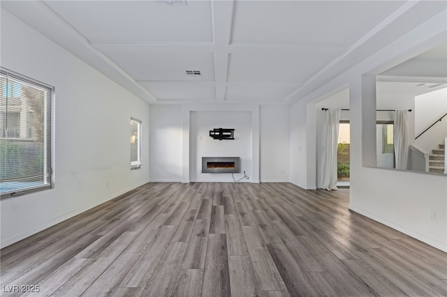 unfurnished living room with coffered ceiling, beam ceiling, and light hardwood / wood-style flooring