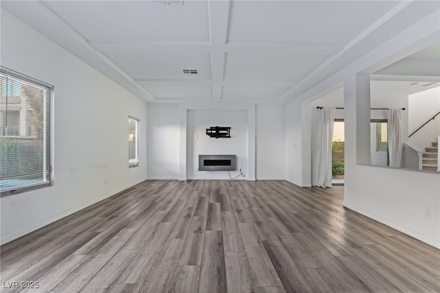 unfurnished living room with beamed ceiling, coffered ceiling, and light wood-type flooring