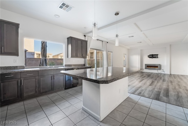 kitchen with light tile patterned flooring, a breakfast bar, decorative light fixtures, dishwasher, and dark brown cabinetry