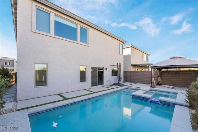 back of property featuring a gazebo and a swimming pool with hot tub