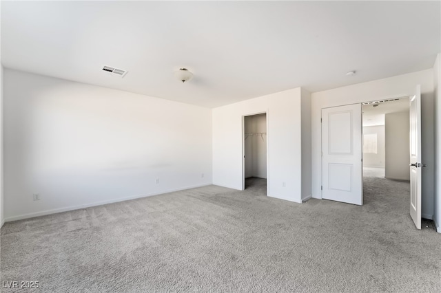 unfurnished bedroom with a spacious closet, light colored carpet, and a closet