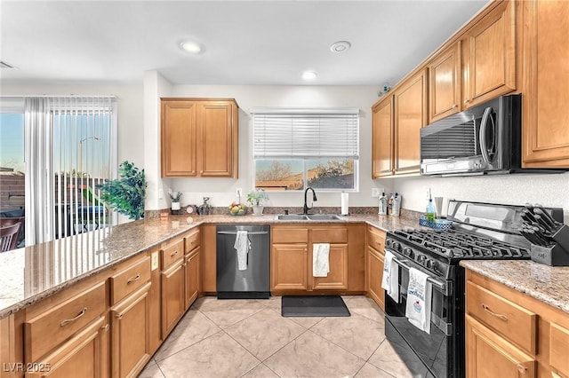 kitchen with sink, light stone counters, light tile patterned floors, black gas range oven, and stainless steel dishwasher