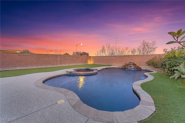 pool at dusk featuring an in ground hot tub and a yard