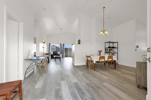 dining room with light hardwood / wood-style floors, high vaulted ceiling, and a chandelier