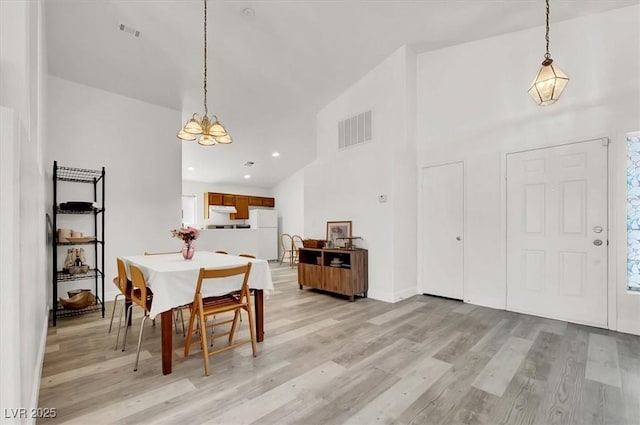 dining room with high vaulted ceiling and light hardwood / wood-style flooring