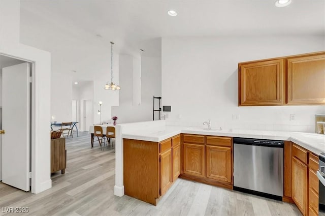 kitchen featuring appliances with stainless steel finishes, hanging light fixtures, light wood-type flooring, sink, and kitchen peninsula