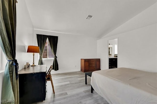 bedroom with light hardwood / wood-style flooring, connected bathroom, and lofted ceiling