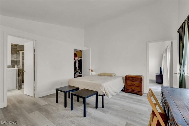 bedroom with light hardwood / wood-style floors, a closet, a high ceiling, and a spacious closet