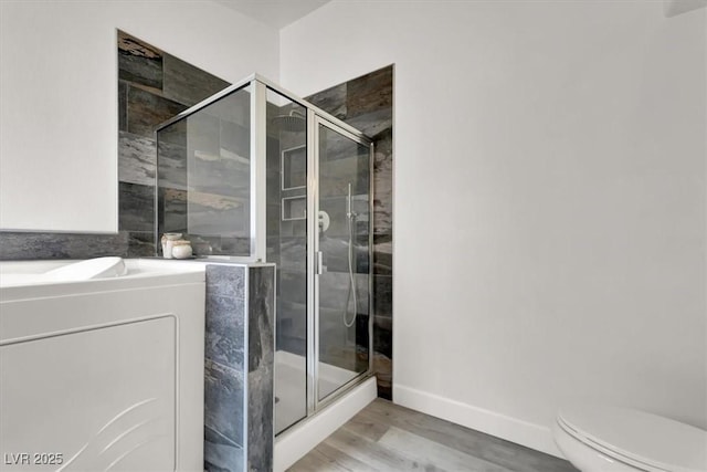 bathroom featuring toilet, a shower with door, and hardwood / wood-style flooring