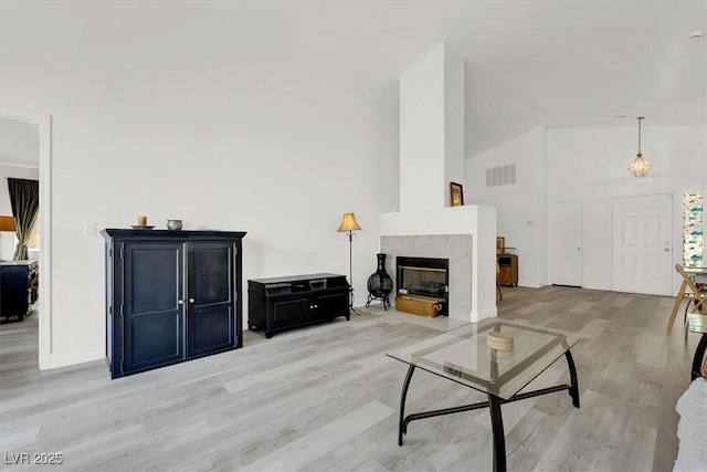 living room featuring a tiled fireplace and light hardwood / wood-style flooring