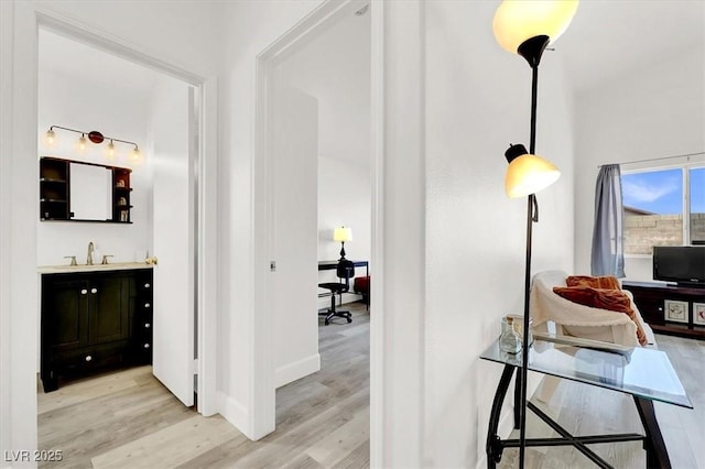 hall with light hardwood / wood-style floors and sink