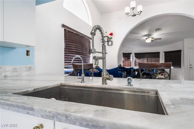 kitchen with ceiling fan with notable chandelier and sink