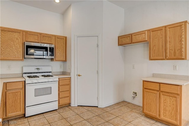 kitchen with white range with gas cooktop, a high ceiling, and light tile patterned flooring