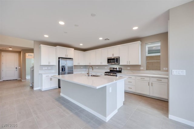 kitchen featuring stainless steel appliances, sink, a center island with sink, and white cabinets