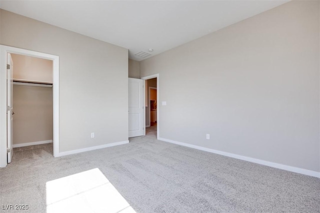 unfurnished bedroom featuring a walk in closet, light colored carpet, and a closet