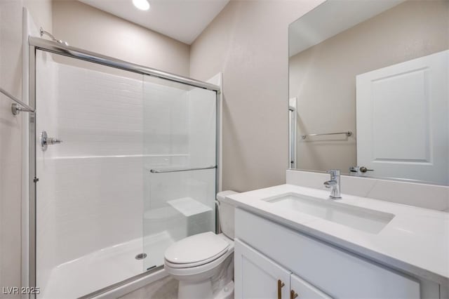 bathroom featuring vanity, a shower with door, and toilet