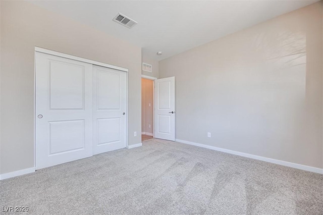 unfurnished bedroom featuring light carpet and a closet