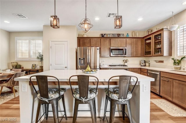 kitchen featuring decorative light fixtures, a breakfast bar, appliances with stainless steel finishes, and a kitchen island