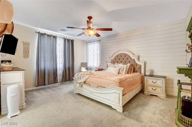 bedroom with wooden walls, light colored carpet, and ceiling fan