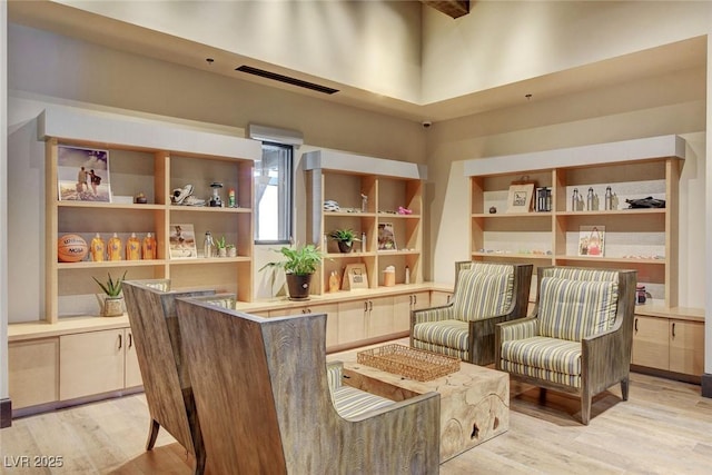 living area with light hardwood / wood-style floors and a towering ceiling