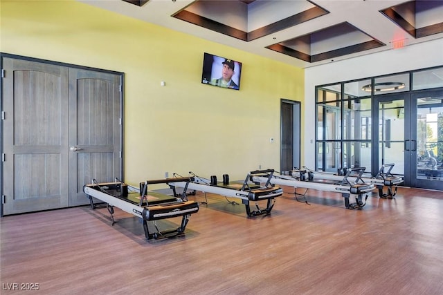 workout area with wood-type flooring, french doors, and coffered ceiling