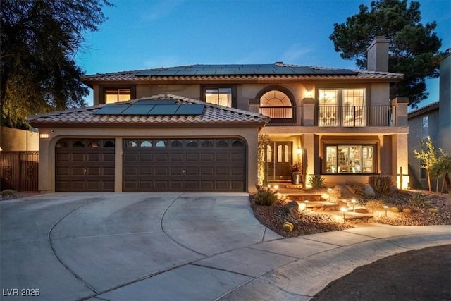 mediterranean / spanish-style home featuring a garage, solar panels, and a balcony