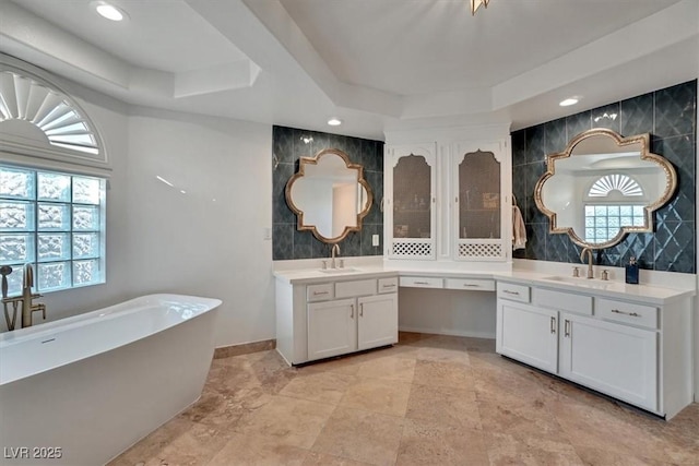 bathroom featuring plenty of natural light, vanity, a tray ceiling, and a washtub