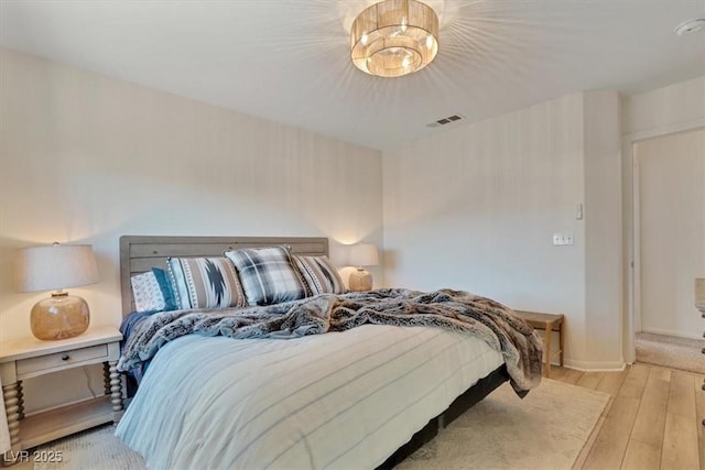 bedroom with a chandelier and light hardwood / wood-style floors