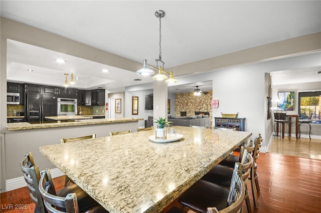 kitchen featuring light stone countertops, a breakfast bar, black fridge, and a raised ceiling