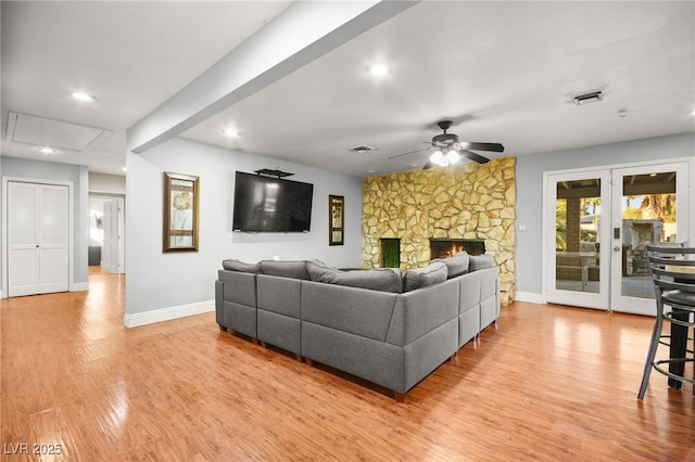 living room featuring a fireplace, light wood-type flooring, and ceiling fan