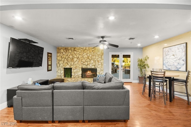 living room featuring wood-type flooring, a fireplace, ceiling fan, and french doors