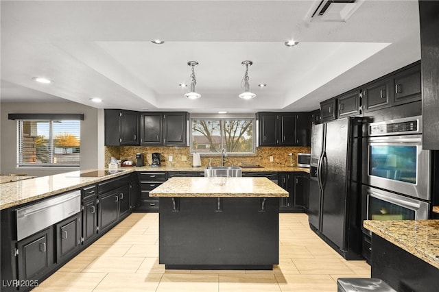 kitchen with decorative light fixtures, black appliances, a raised ceiling, and a kitchen island