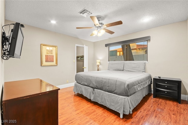 bedroom with light hardwood / wood-style floors, a textured ceiling, and ceiling fan