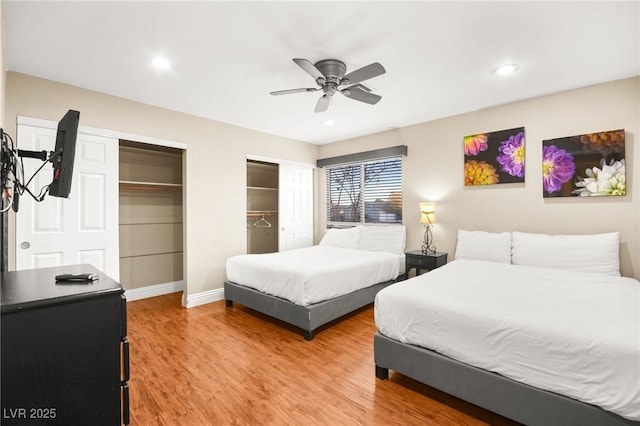 bedroom featuring hardwood / wood-style flooring, two closets, and ceiling fan