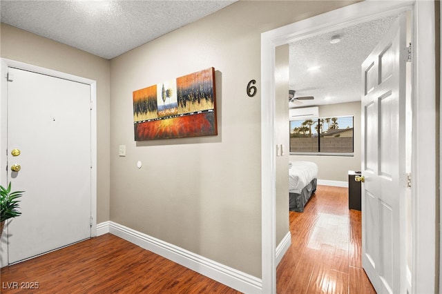 foyer featuring hardwood / wood-style flooring, a textured ceiling, an AC wall unit, and ceiling fan