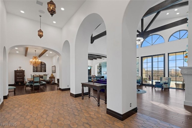 foyer entrance featuring beam ceiling, baseboards, a towering ceiling, and dark wood-style flooring