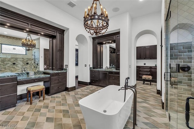 full bathroom with a chandelier, a stall shower, a freestanding tub, and vanity