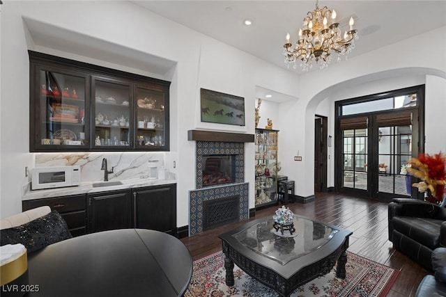 living area with arched walkways, french doors, a fireplace, recessed lighting, and dark wood-type flooring