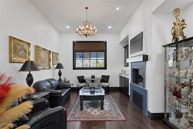 living room with a tile fireplace, dark wood finished floors, baseboards, and an inviting chandelier