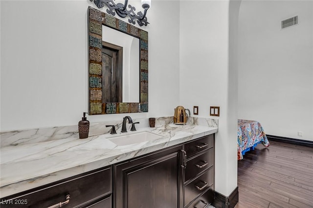 bathroom with visible vents, wood finished floors, vanity, and baseboards