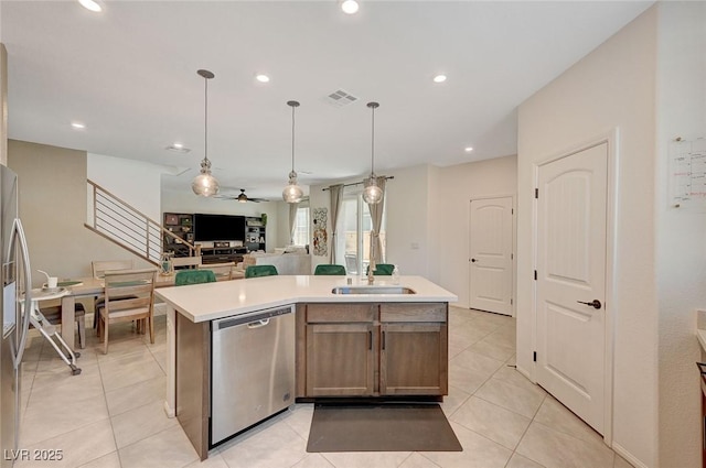 kitchen featuring decorative light fixtures, sink, light tile patterned floors, a center island with sink, and stainless steel appliances