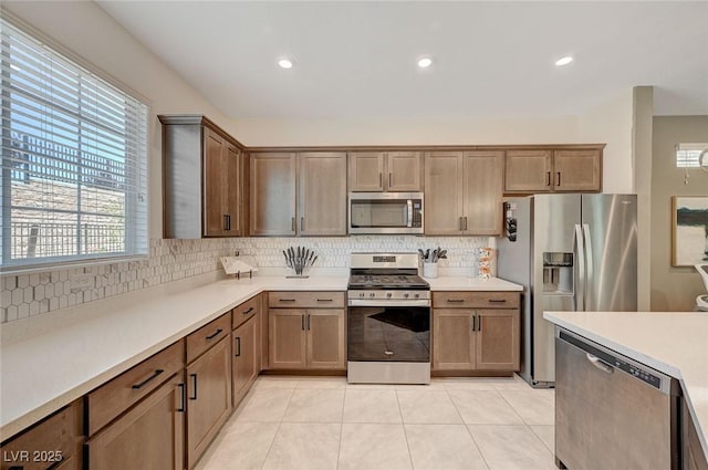 kitchen with decorative backsplash, light tile patterned floors, appliances with stainless steel finishes, and a healthy amount of sunlight