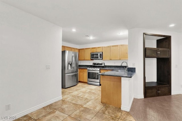 kitchen with stainless steel appliances, dark stone countertops, sink, kitchen peninsula, and light tile patterned floors