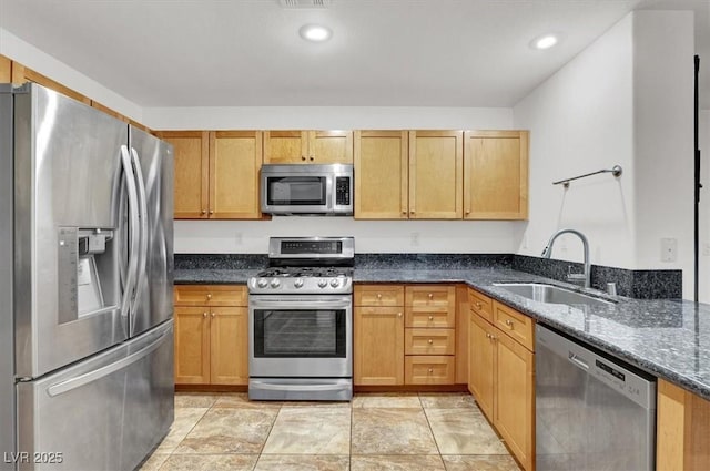 kitchen featuring sink, appliances with stainless steel finishes, and dark stone counters