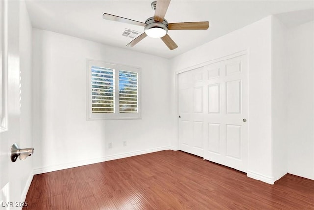 unfurnished bedroom featuring dark wood-type flooring, a closet, and ceiling fan