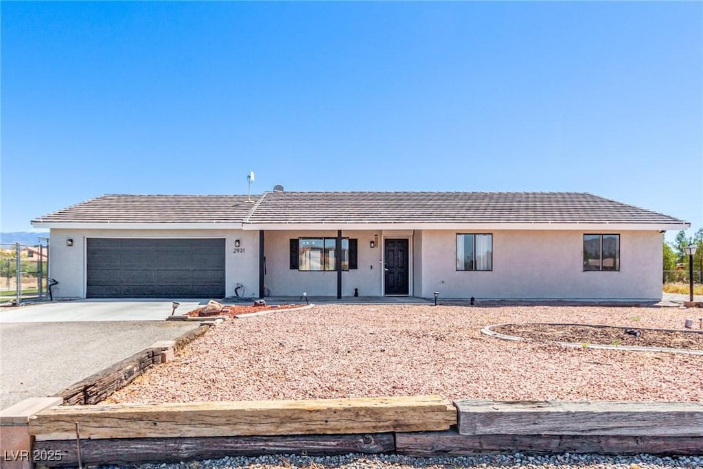 ranch-style house featuring driveway, stucco siding, an attached garage, and a tiled roof