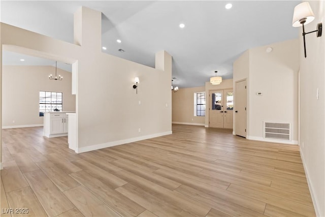 unfurnished living room featuring vaulted ceiling, a chandelier, and light hardwood / wood-style flooring