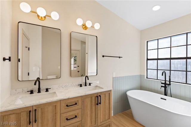 bathroom with vanity, a bathtub, and tile walls