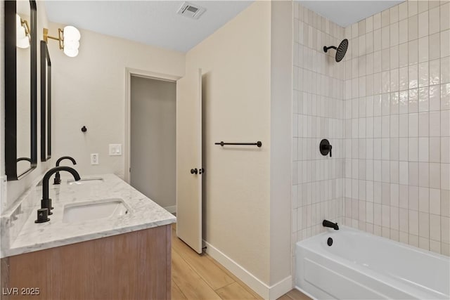 bathroom featuring tiled shower / bath combo, vanity, and wood-type flooring