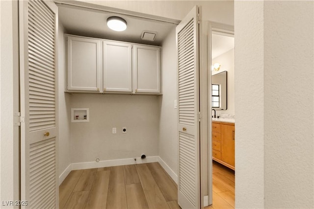 washroom with cabinets, washer hookup, hookup for an electric dryer, and light hardwood / wood-style floors